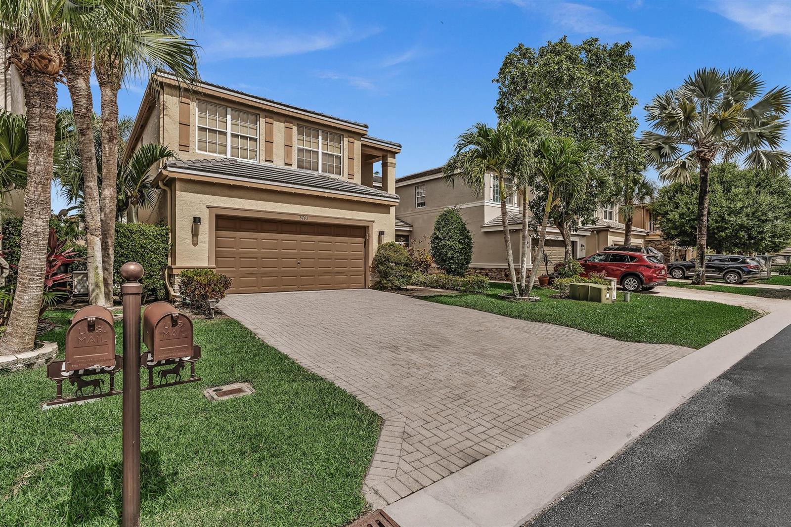 A two-story suburban house with a paved driveway, a two-car garage, and palm trees — 5743 Raceway Road, Lake Worth FL 33449, LAKE WORTH, FL