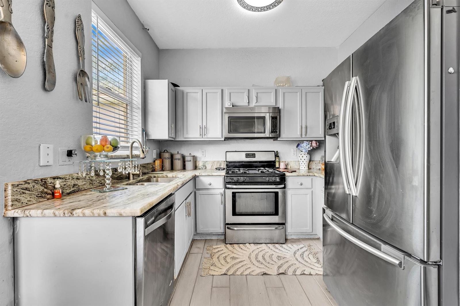 A kitchen features light gray cabinets, stainless steel appliances, and granite countertops — 5743 Raceway Road, Lake Worth FL 33449, LAKE WORTH, FL