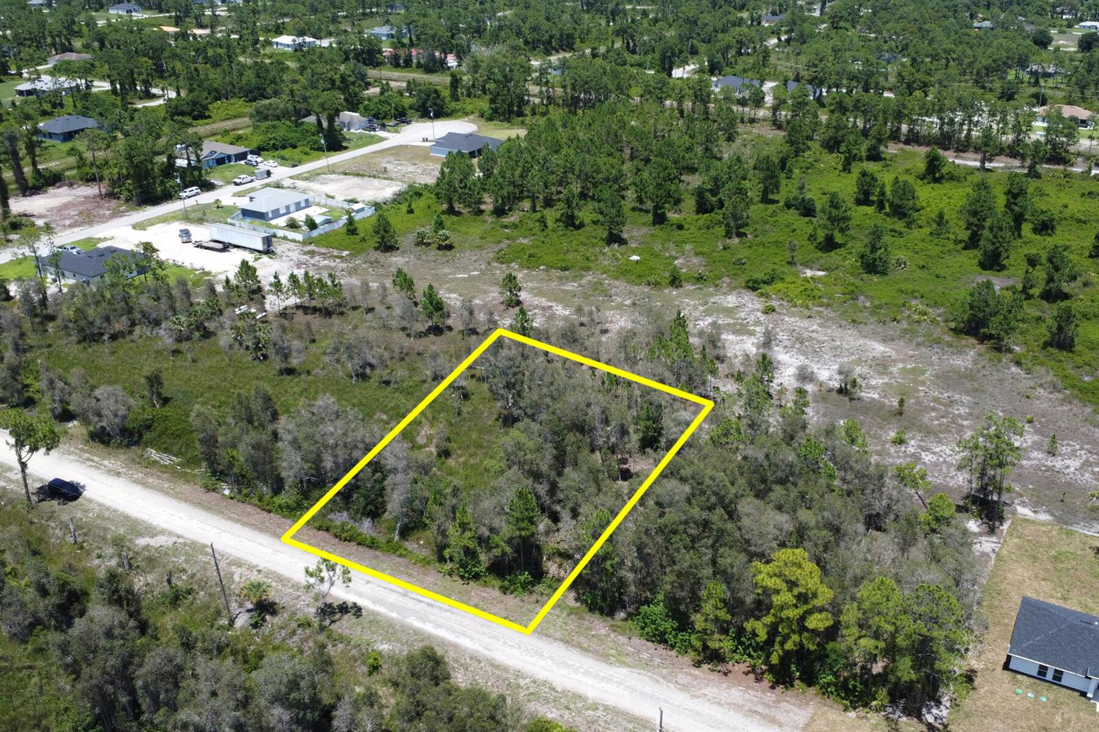 An aerial view shows a rectangular, wooded vacant lot outlined in yellow along a road — 859 Burrows Avenue, Lehigh Acres FL 33974, LEHIGH ACRES, FL