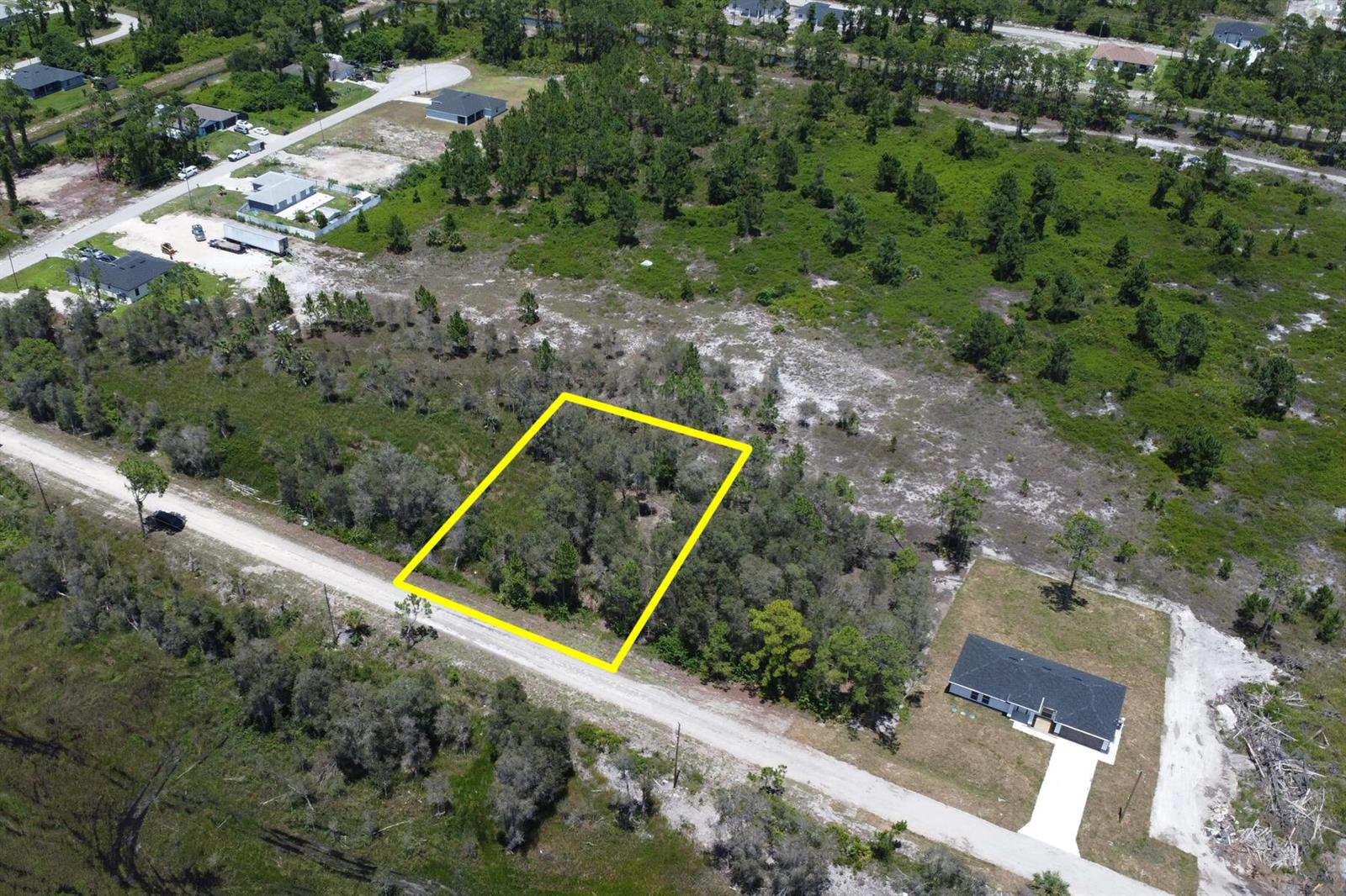 An aerial view shows a vacant, wooded rectangular lot outlined in yellow along a road — 859 Burrows Avenue, Lehigh Acres FL 33974, LEHIGH ACRES, FL