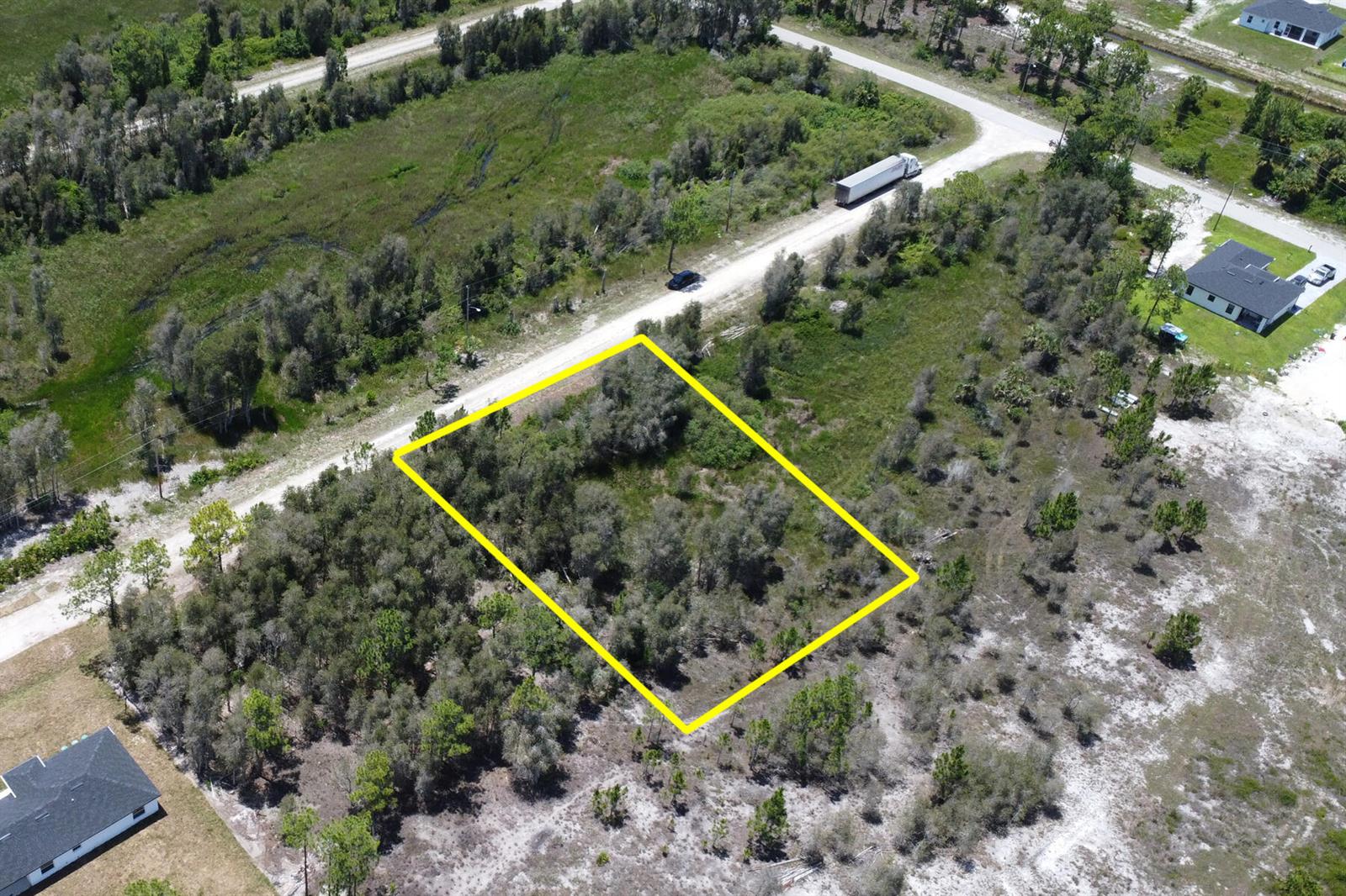 An aerial view shows a rectangular plot of land outlined in yellow near a road — 859 Burrows Avenue, Lehigh Acres FL 33974, LEHIGH ACRES, FL