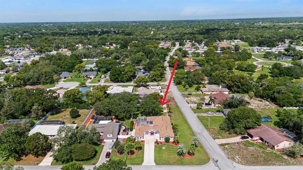 An aerial view shows a suburban house with a pool and a red arrow pointing down — 10339 BEDFORD ROAD, SPRING HILL, FL
