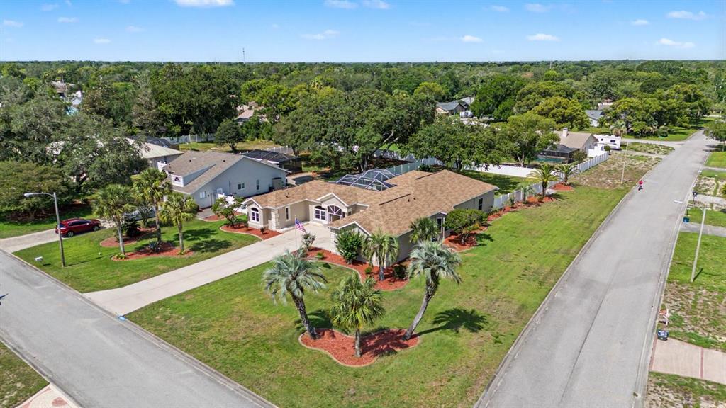 An aerial view shows a single-story house with a pool enclosure and a corner lot — 10339 BEDFORD ROAD, SPRING HILL, FL