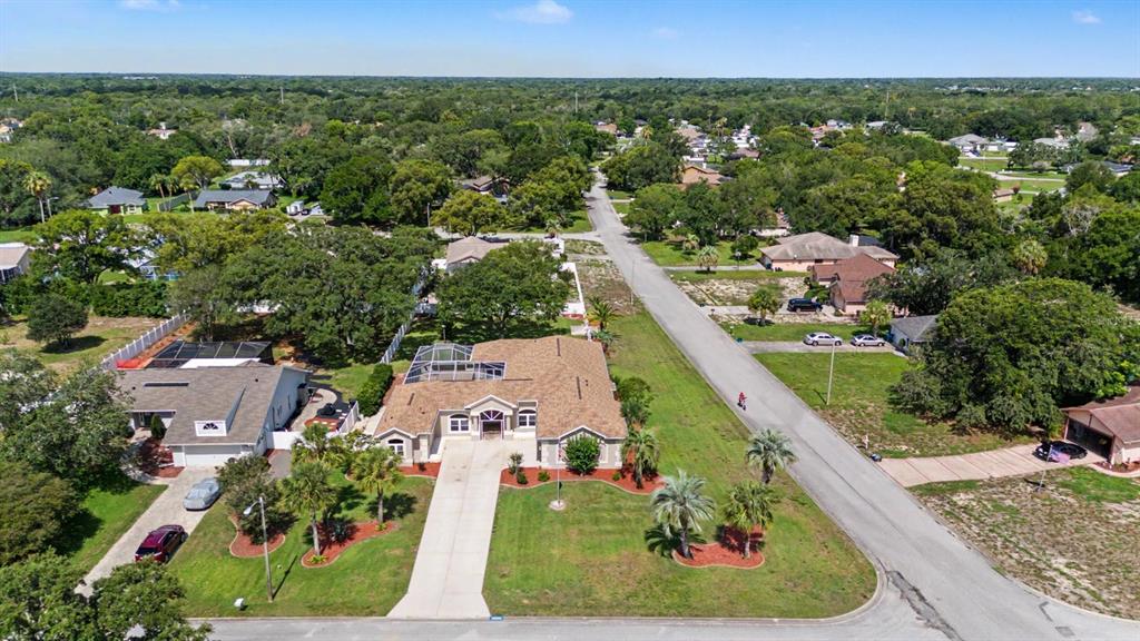 An aerial view shows a single-story house with a tan roof and a screened-in pool — 10339 BEDFORD ROAD, SPRING HILL, FL