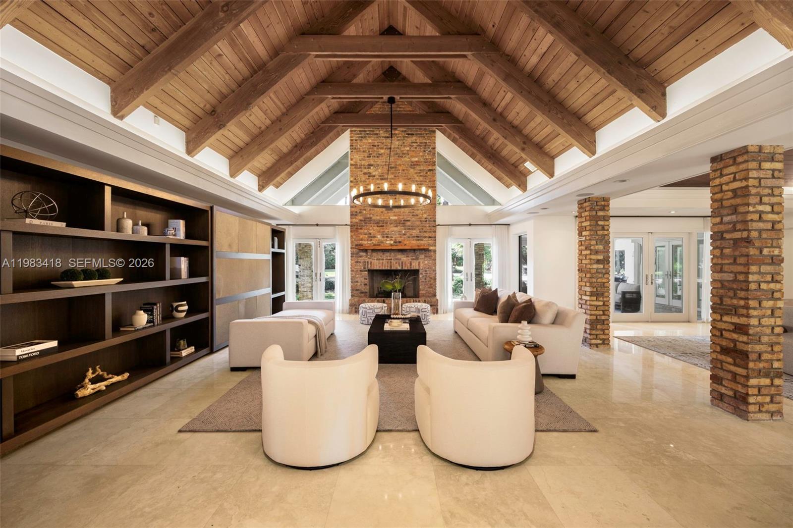 A living room features a vaulted wood-beam ceiling, a brick fireplace, and built-in shelving — 9000 Arvida Dr, Coral Gables FL 33156, CORAL GABLES, FL