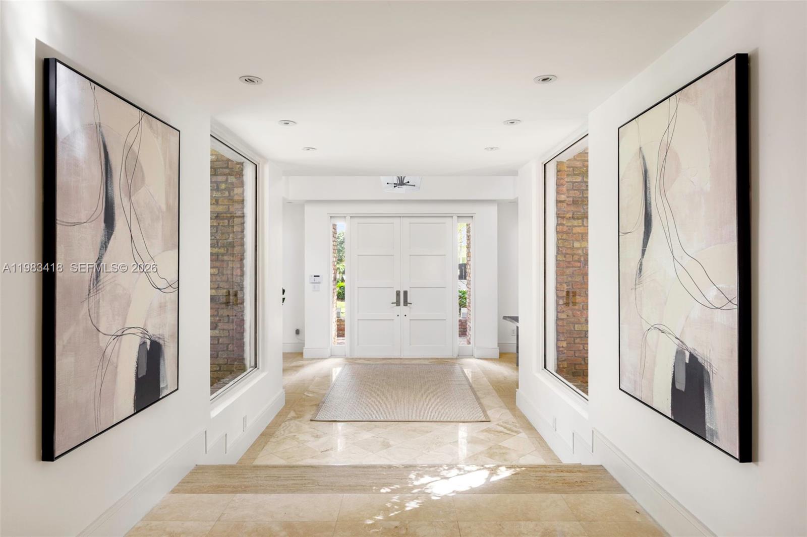 A bright entryway features a double door, stone flooring, and two large abstract wall paintings — 9000 Arvida Dr, Coral Gables FL 33156, CORAL GABLES, FL