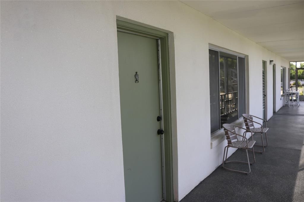 A light green door and two metal chairs sit on a covered outdoor walkway — 1700 6TH STREET NW UNIT B23, WINTER HAVEN, FL