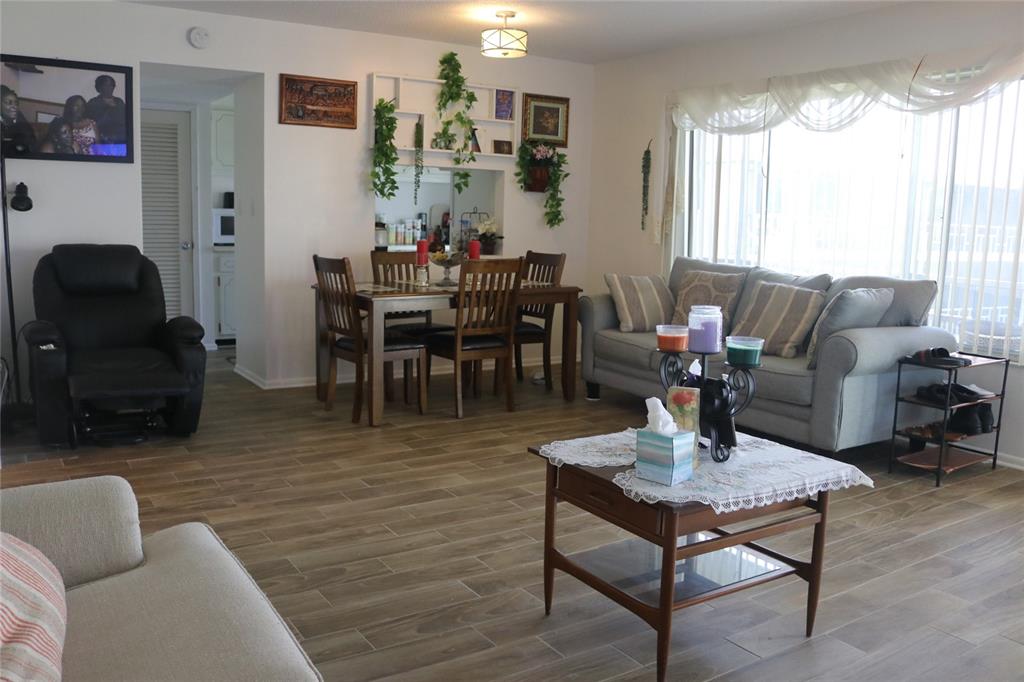 A living room and dining area feature wood-look tile flooring and neutral walls — 1700 6TH STREET NW UNIT B23, WINTER HAVEN, FL