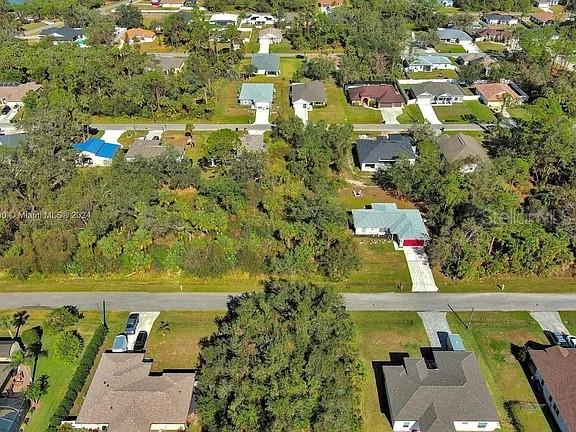 This aerial view shows a suburban neighborhood with houses, trees, and paved streets — SARGON AVENUE, NORTH PORT, FL