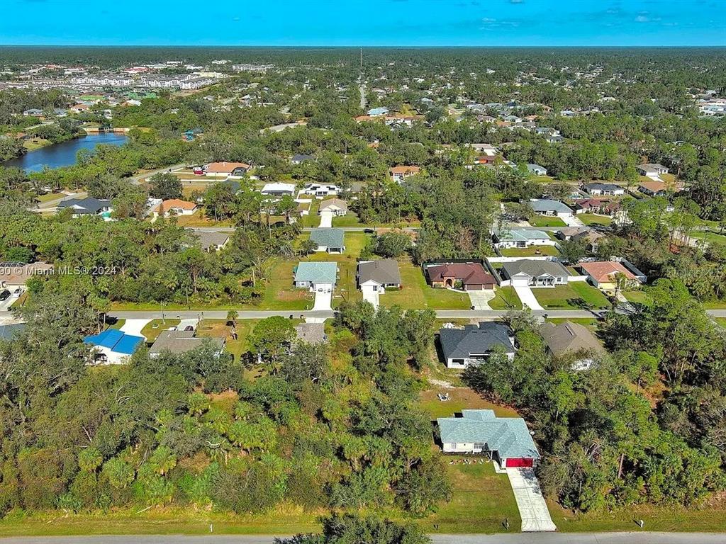 An aerial view shows a suburban neighborhood with single-family homes surrounded by dense trees — SARGON AVENUE, NORTH PORT, FL