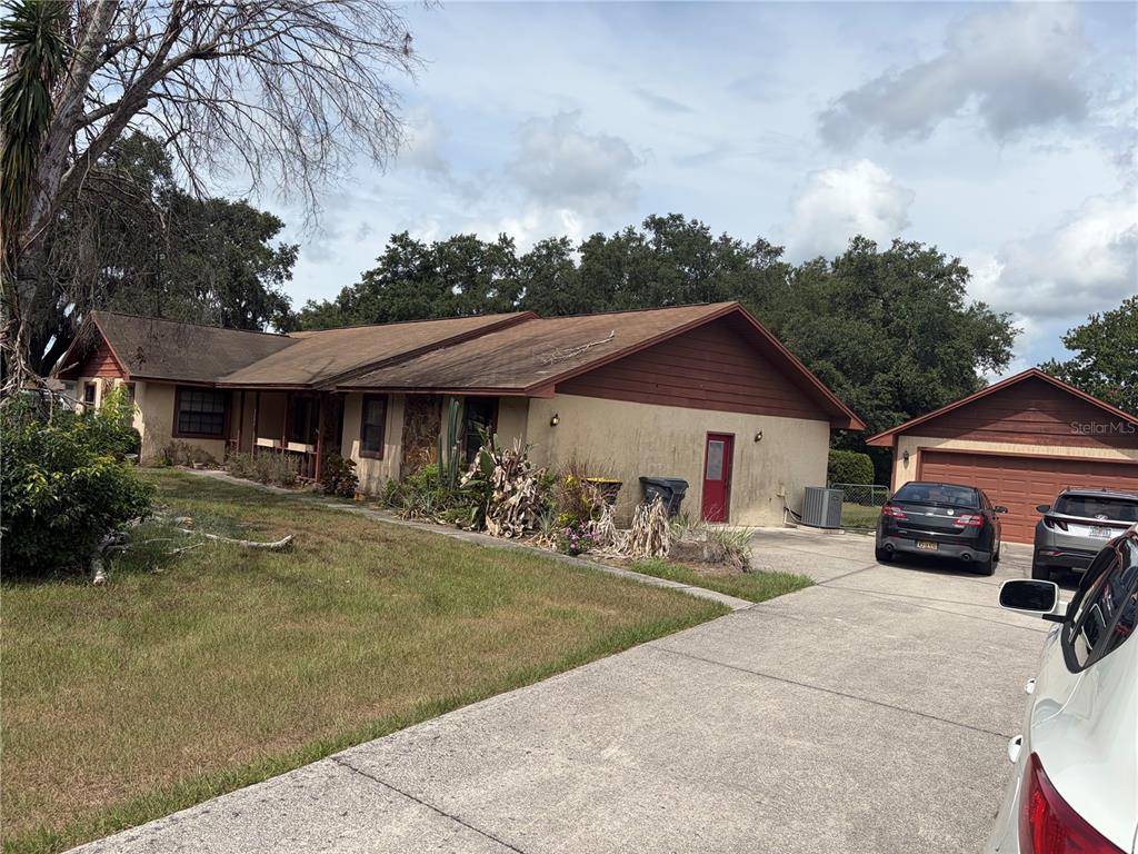 A single-story house with a tan stucco exterior, brown trim, and a detached two-car garage — 4253 STAFFORD DRIVE, WINTER HAVEN, FL