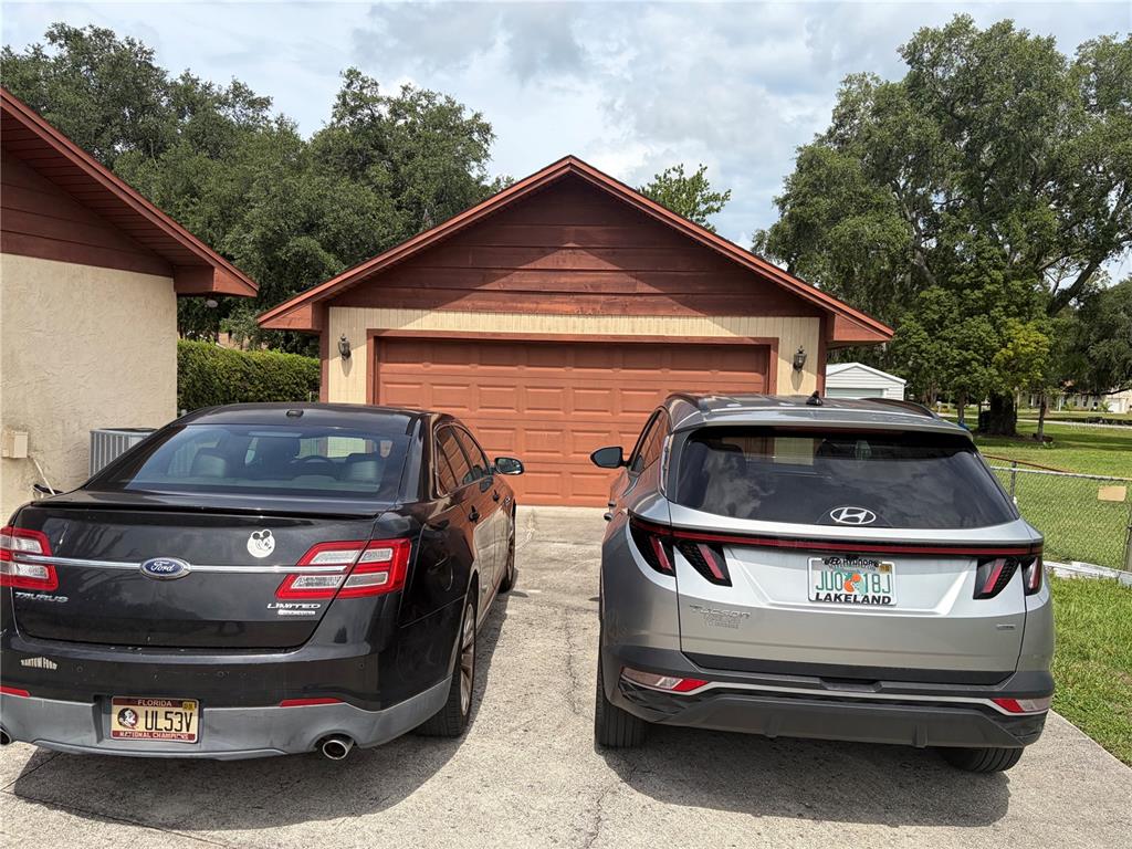 A black sedan and a silver SUV are parked in a driveway before a garage — 4253 STAFFORD DRIVE, WINTER HAVEN, FL