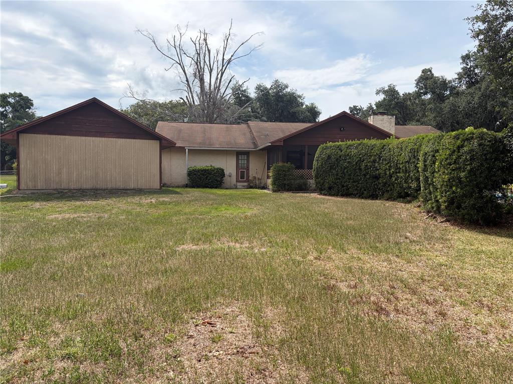 A single-story house with a brown roof, wood siding, and a large backyard lawn — 4253 STAFFORD DRIVE, WINTER HAVEN, FL