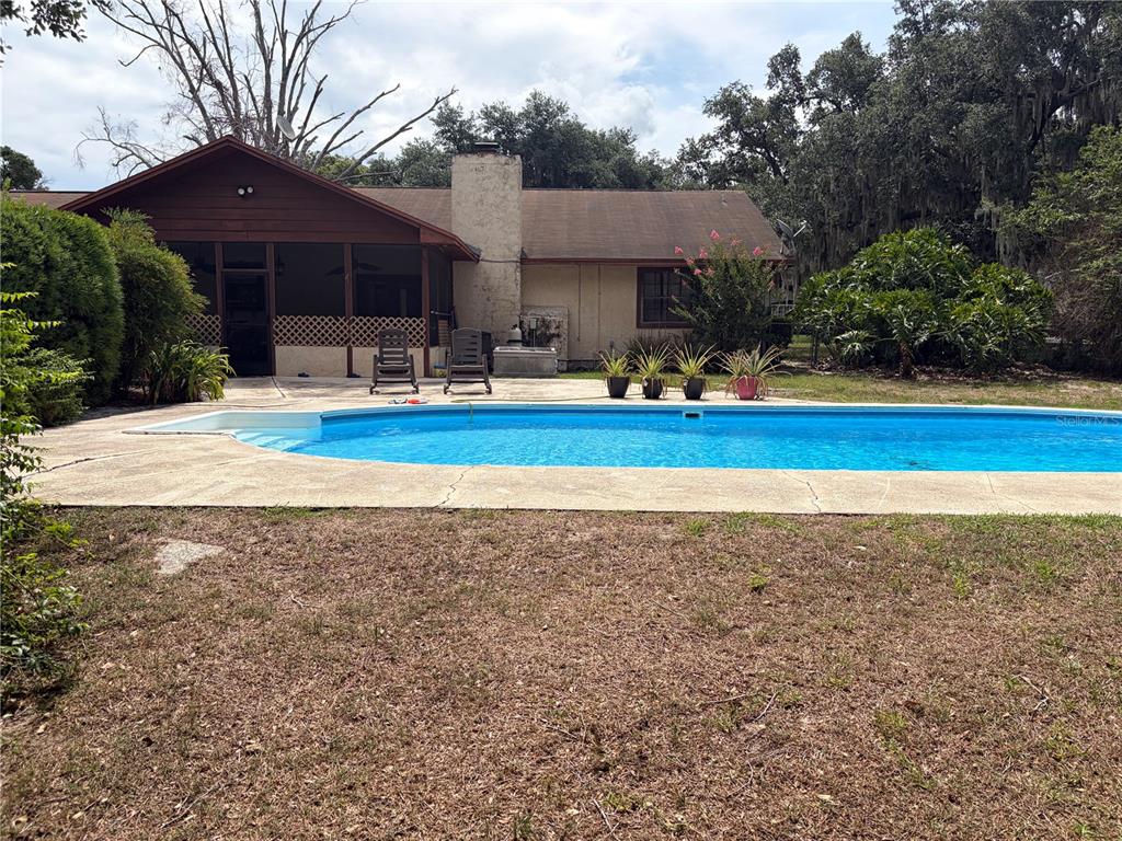 A backyard features a swimming pool, a screened-in porch, and a stucco house exterior — 4253 STAFFORD DRIVE, WINTER HAVEN, FL
