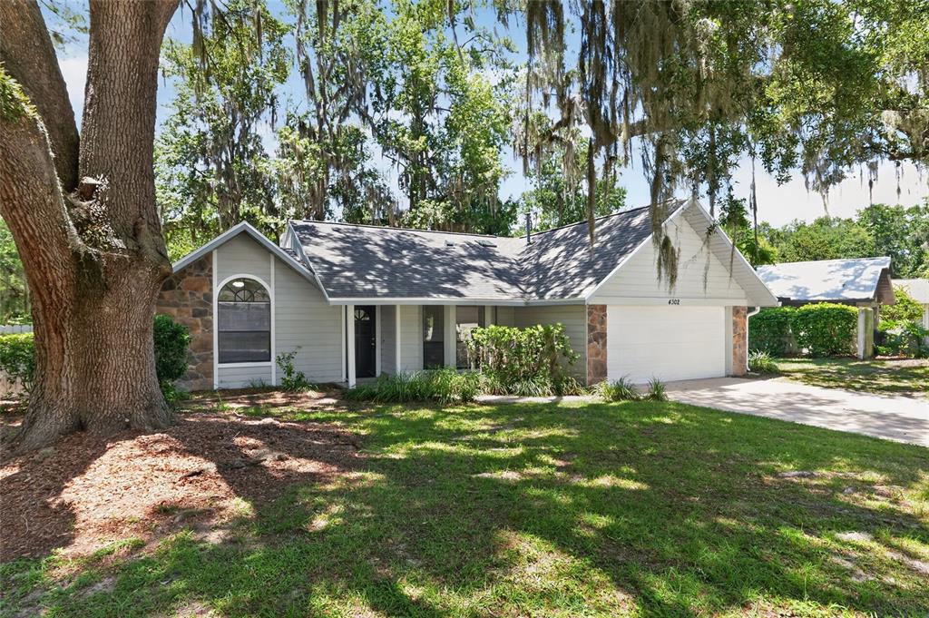 A single-story house with light gray siding, stone accents, and a two-car garage — 4302 NW 61ST TERRACE, GAINESVILLE, FL