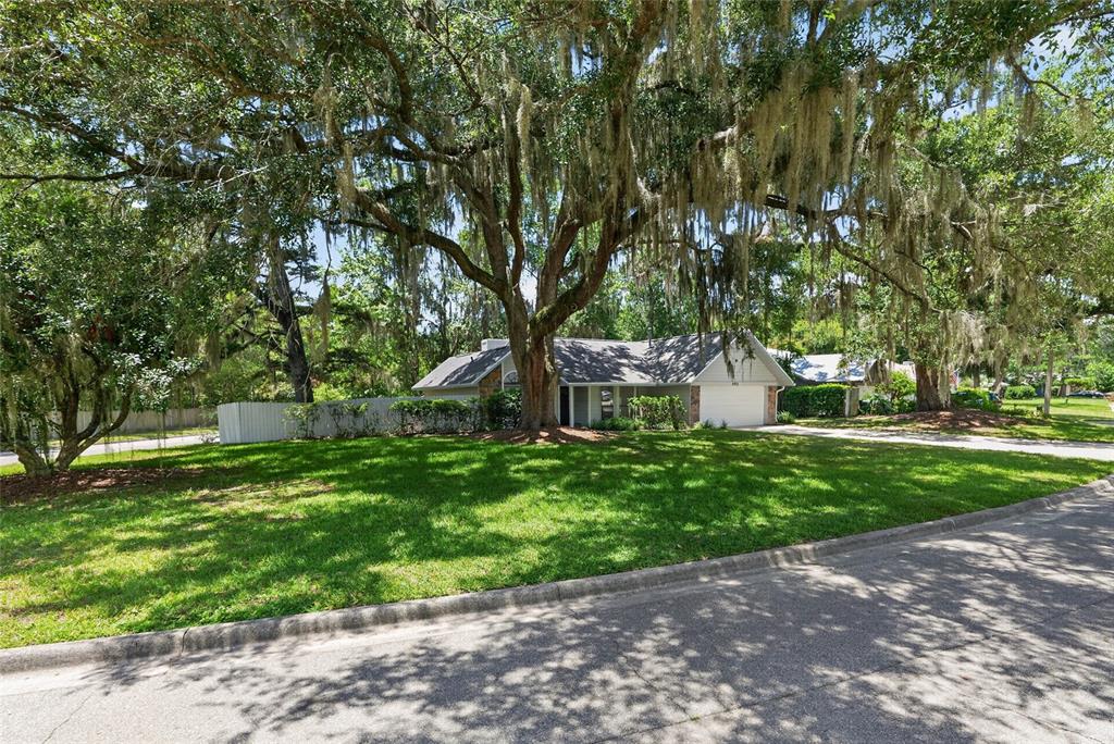 A single-story house with a white garage and large oak trees in the front yard — 4302 NW 61ST TERRACE, GAINESVILLE, FL