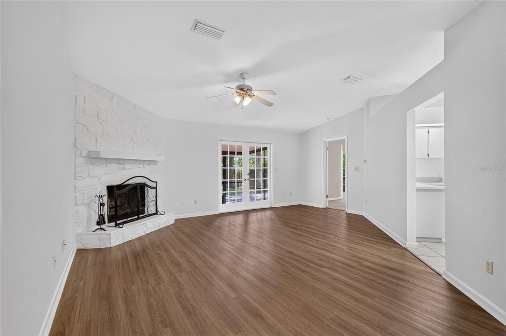 A living room features wood-look flooring, a white stone fireplace, and glass French doors — 4302 NW 61ST TERRACE, GAINESVILLE, FL