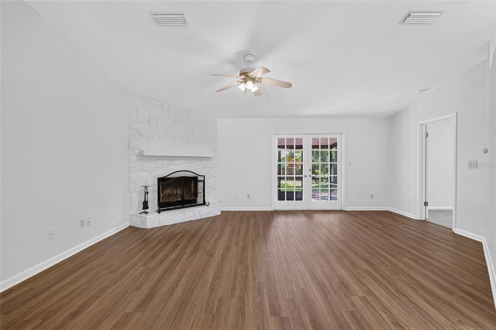 A living room with wood-look flooring, a white stone fireplace, and glass-paned double doors — 4302 NW 61ST TERRACE, GAINESVILLE, FL