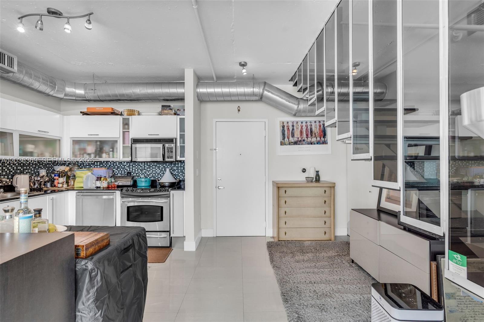 A kitchen and living area feature white cabinets, exposed ductwork, and a gray area rug — 690 SW 1st Ct, Miami FL 33130, MIAMI, FL