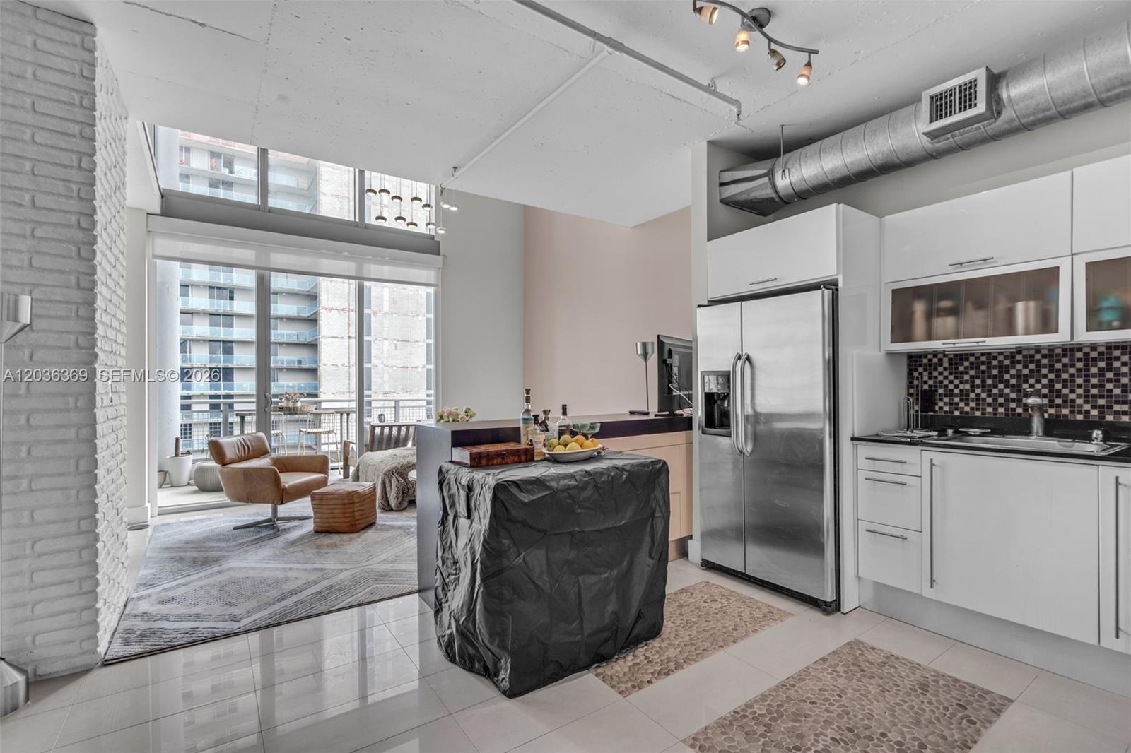 A modern kitchen and living area feature white cabinetry, stainless appliances, and floor-to-ceiling windows — 690 SW 1st Ct, Miami FL 33130, MIAMI, FL
