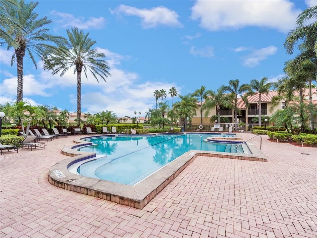An outdoor swimming pool is surrounded by a brick patio, palm trees, and apartment buildings — 1235 SW 46th Ave # 707, Pompano Beach FL 33069, POMPANO BEACH, FL