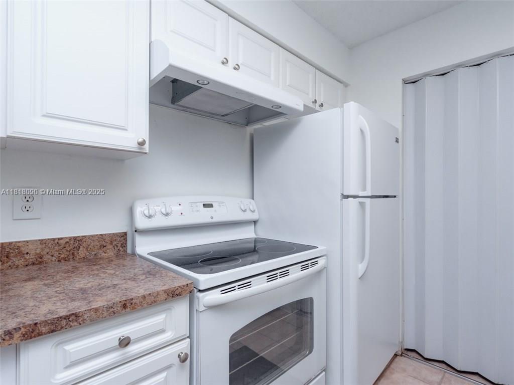 A kitchen features white cabinets, a white electric range, and a white refrigerator — 1235 SW 46th Ave # 707, Pompano Beach FL 33069, POMPANO BEACH, FL