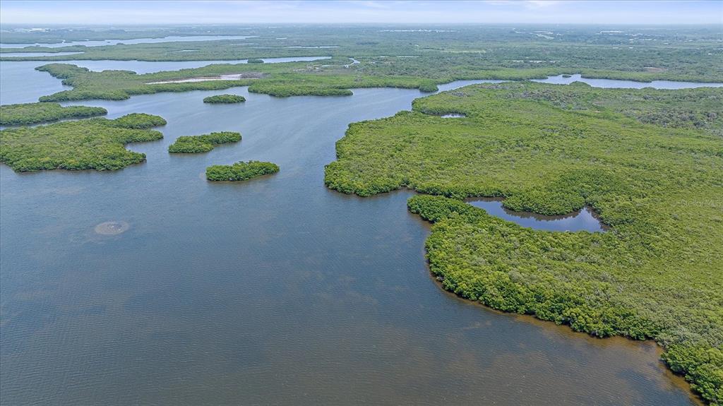 An aerial view of a coastal landscape featuring dense mangrove islands surrounded by open water — STOTZ ROAD, PALMETTO, FL