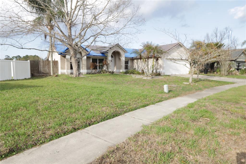 A single-story house with a blue tarp on the roof and a front lawn — 11346 CYPRESS LEAF DR. DRIVE, ORLANDO, FL