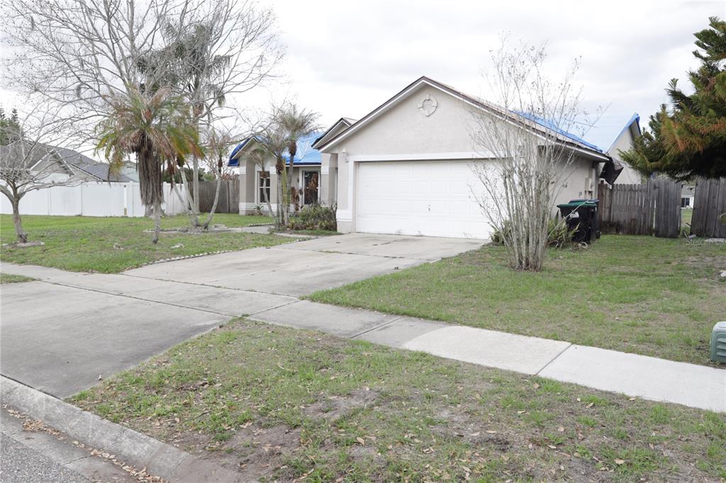 A single-story house with a two-car garage and a blue tarp on the roof — 11346 CYPRESS LEAF DR. DRIVE, ORLANDO, FL
