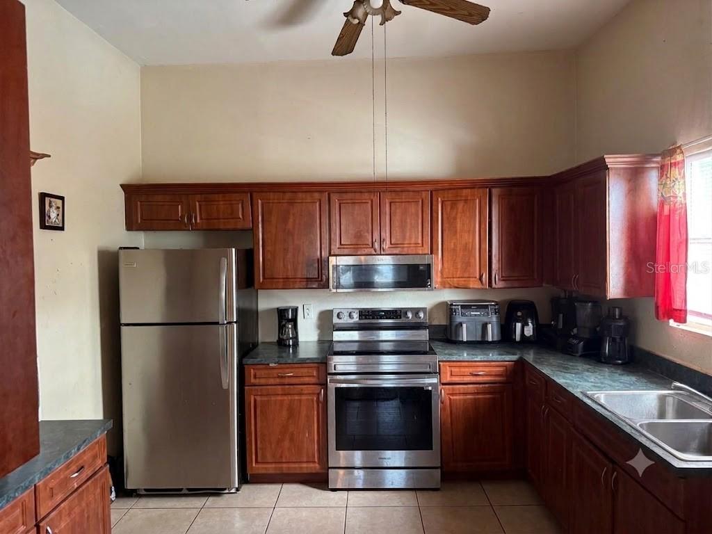 A kitchen features wooden cabinets, stainless steel appliances, and tiled flooring — 1410 E 21ST AVENUE, TAMPA, FL