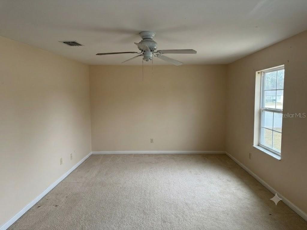 An empty bedroom features beige walls, beige carpeting, a ceiling fan, and a single window — 1410 E 21ST AVENUE, TAMPA, FL