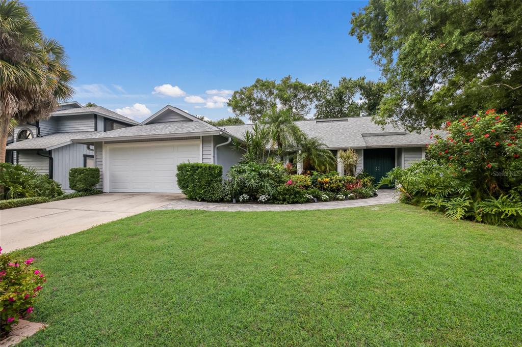 A gray single-story house with a white garage door and lush landscaping in the front — 851 FAULKWOOD COURT, SARASOTA, FL