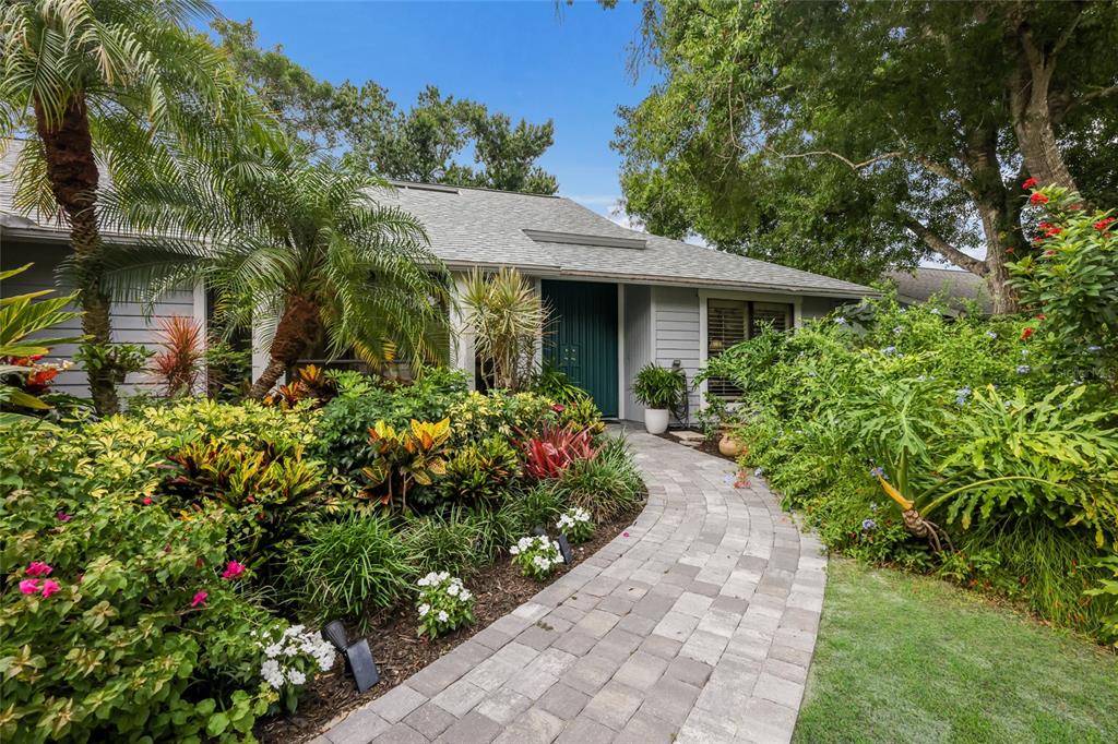 A paved walkway leads to the front entrance of a house surrounded by lush landscaping — 851 FAULKWOOD COURT, SARASOTA, FL