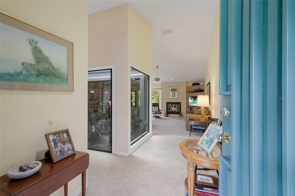 An entryway with tile flooring leads into a living room with a fireplace and windows — 851 FAULKWOOD COURT, SARASOTA, FL