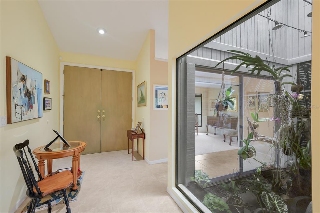 An entryway with tile floors features a wooden double door and an indoor glass-enclosed atrium — 851 FAULKWOOD COURT, SARASOTA, FL