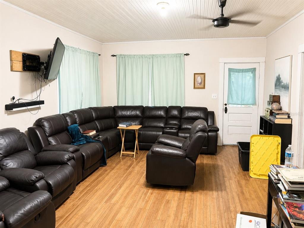 A living room features a large dark leather sectional, wood flooring, and a wall-mounted television — 129 S MILLS AVENUE, ARCADIA, FL