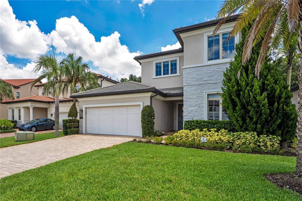A two-story house with a stone facade, a two-car garage, and a paved driveway — 10654 ROYAL CYPRESS WAY, ORLANDO, FL