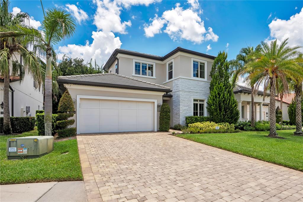 A two-story house with a paved driveway, a white garage door, and stone accents — 10654 ROYAL CYPRESS WAY, ORLANDO, FL