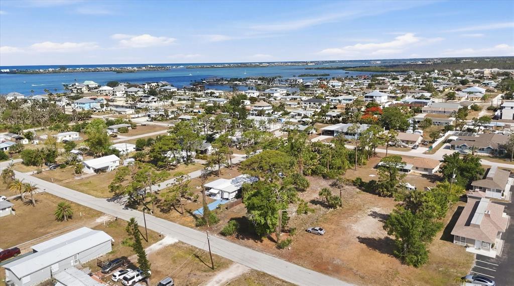 An aerial view shows a residential neighborhood with houses, trees, and a nearby coastal waterway — 1970 KENTUCKY AVENUE, ENGLEWOOD, FL