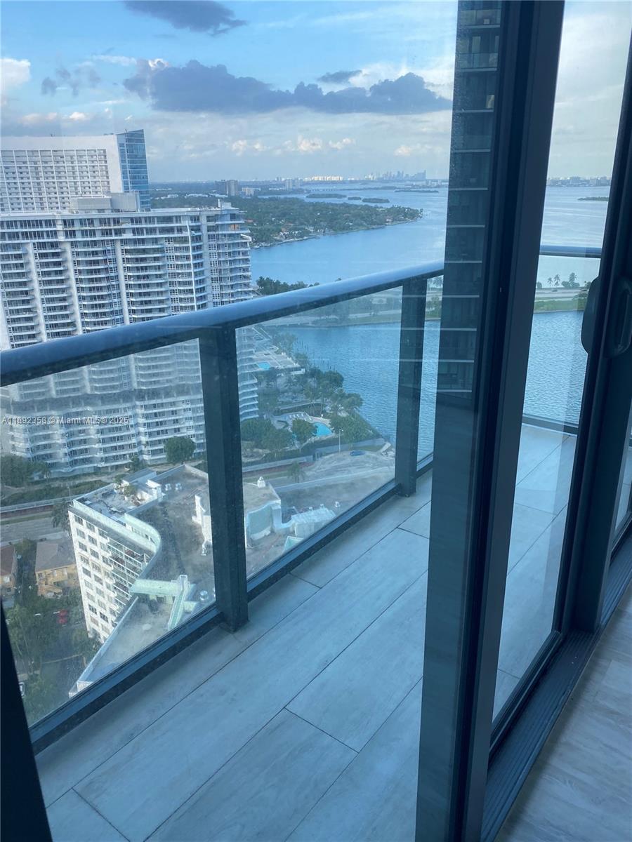 A balcony with glass railings overlooks a bay, high-rise buildings, and a swimming pool — 650 NE 32nd St # 3108, Miami FL 33137, MIAMI, FL