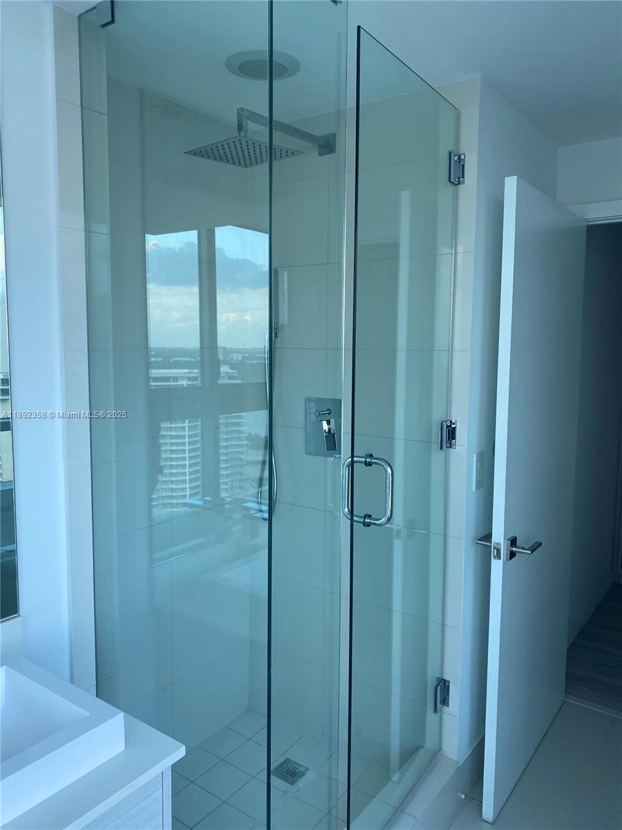 A modern glass-enclosed shower features a rainfall showerhead and white tiled walls — 650 NE 32nd St # 3108, Miami FL 33137, MIAMI, FL