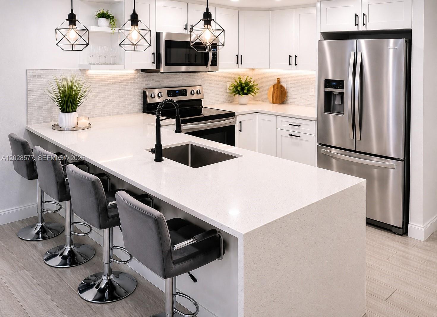 A modern kitchen features white cabinets, quartz countertops, stainless steel appliances, and a breakfast bar — 14311 N Kendall Dr # 206A, Miami FL 33186, MIAMI, FL