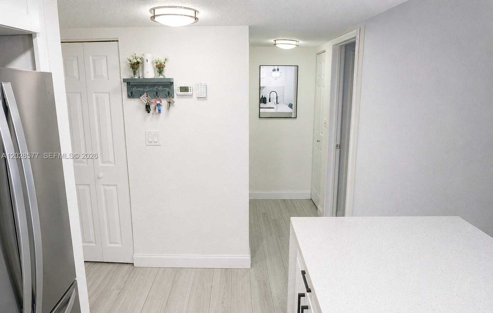 A kitchen area features a white wall with a key rack, thermostat, and hallway access — 14311 N Kendall Dr # 206A, Miami FL 33186, MIAMI, FL