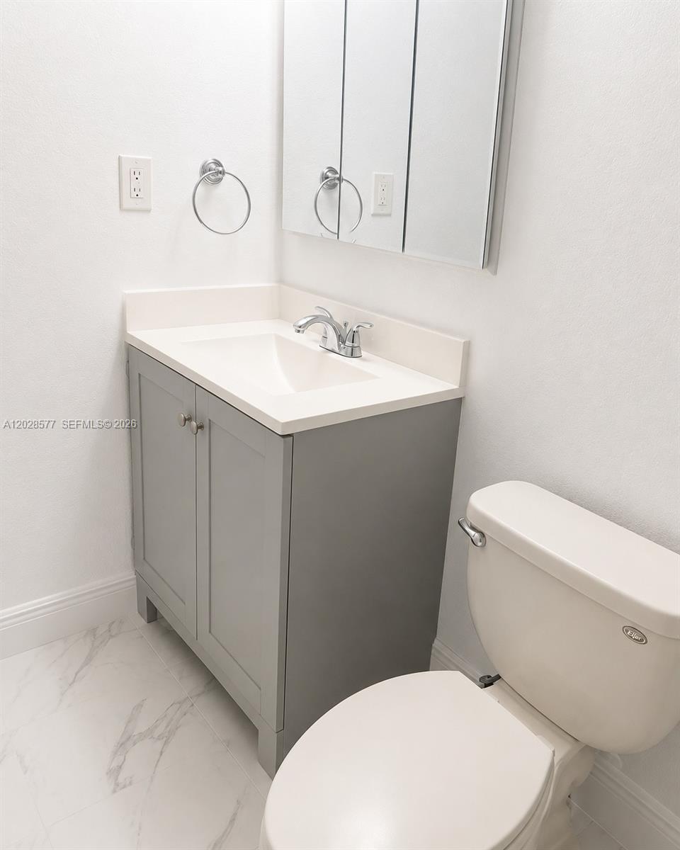 A bathroom features a gray vanity, white countertop, sink, toilet, and a mirrored medicine cabinet — 14311 N Kendall Dr # 206A, Miami FL 33186, MIAMI, FL