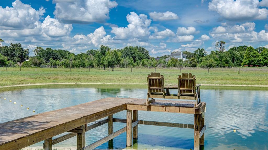 A wooden dock with two chairs extends over a pond in a grassy field — 560 OAKFORD ROAD, SARASOTA, FL