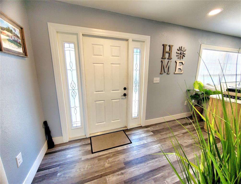 An entryway features a white front door with sidelights, gray walls, and wood-look flooring — 2837 LONGLEAF LANE, PALM HARBOR, FL