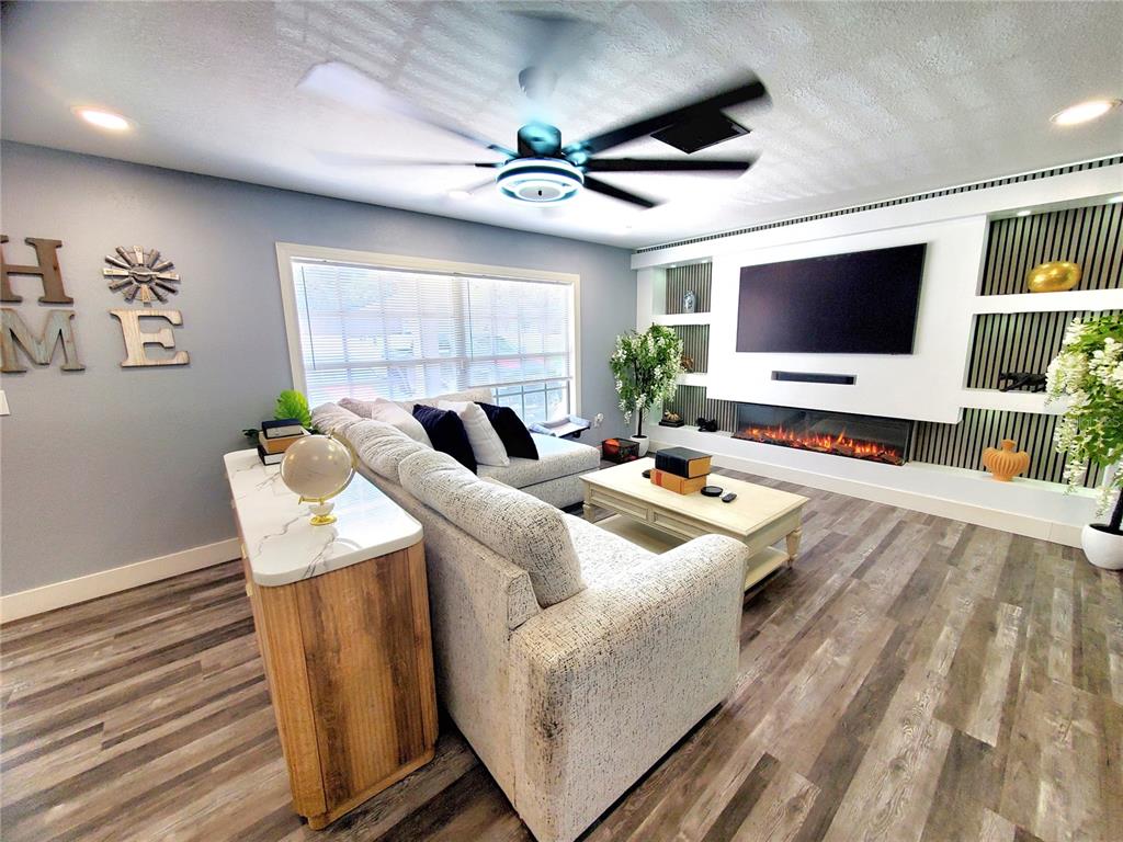 A living room features a sectional sofa, a fireplace, and a wall-mounted television — 2837 LONGLEAF LANE, PALM HARBOR, FL