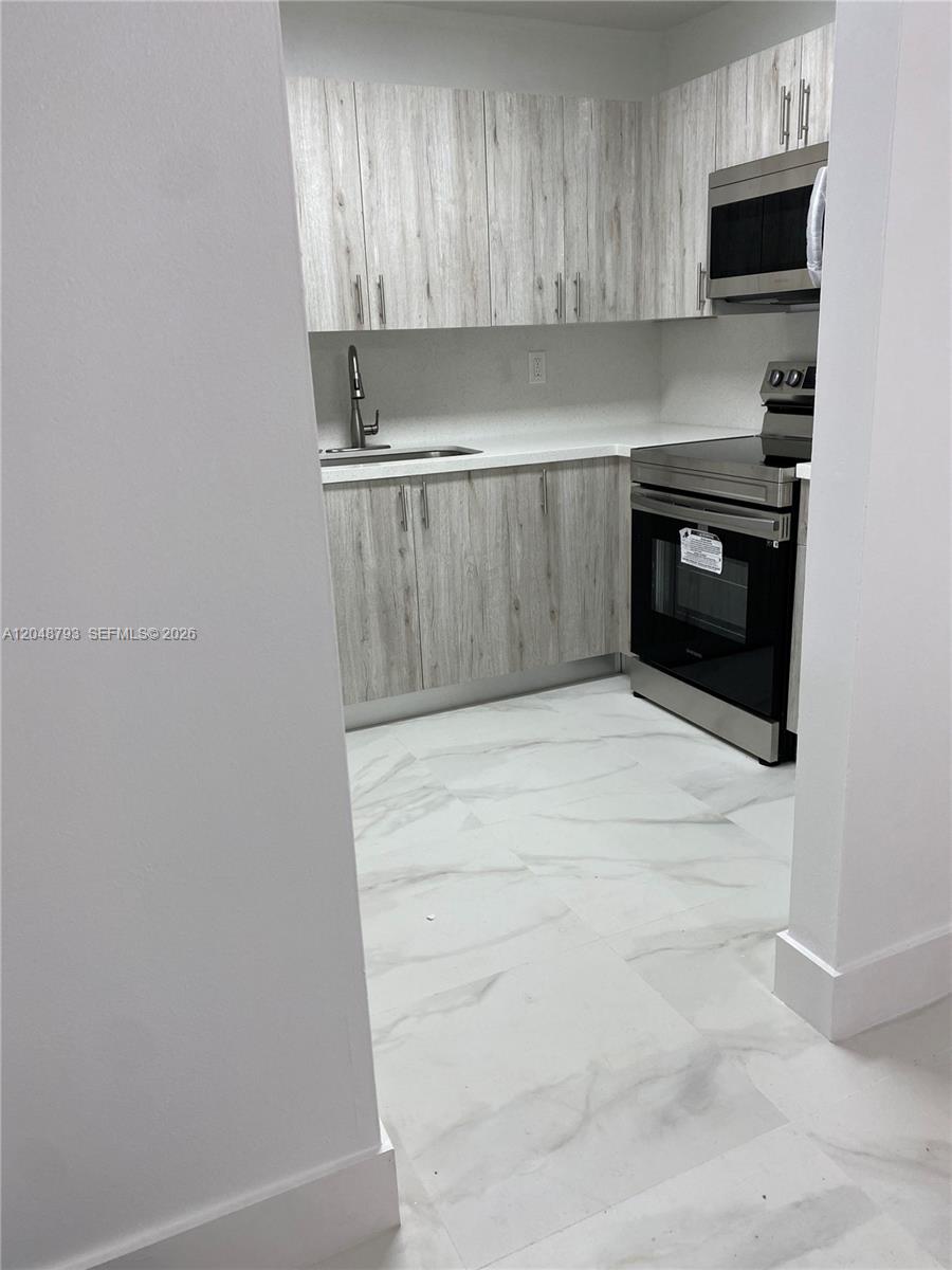A kitchen features light wood-grain cabinets, white countertops, and stainless steel appliances — 6190 W 19th Ave # 206, Hialeah FL 33012, HIALEAH, FL