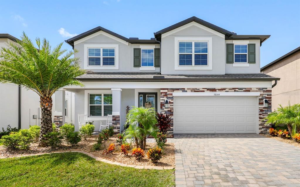 A two-story house with a stone-accented facade, a paved driveway, and a front palm tree — 38144 COBBLE CREEK BOULEVARD, ZEPHYRHILLS, FL