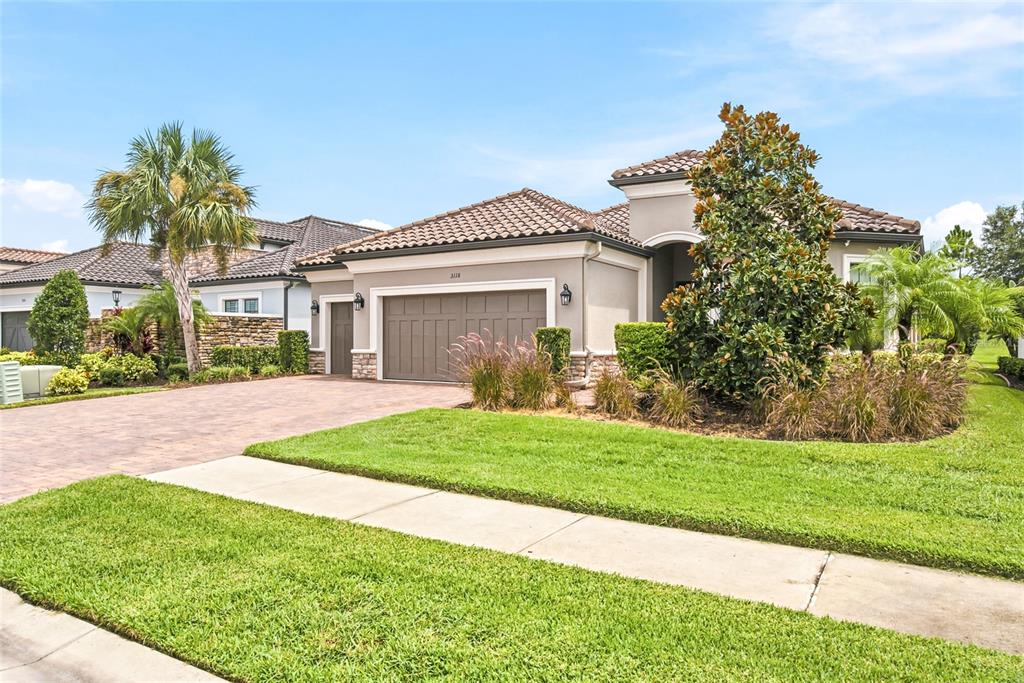 A single-story house with a brown garage, tile roof, and landscaped front yard — 3118 FORSYTHIA DRIVE, ODESSA, FL